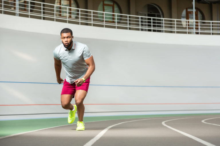 Energetic professional young male runner in stylish sneakers