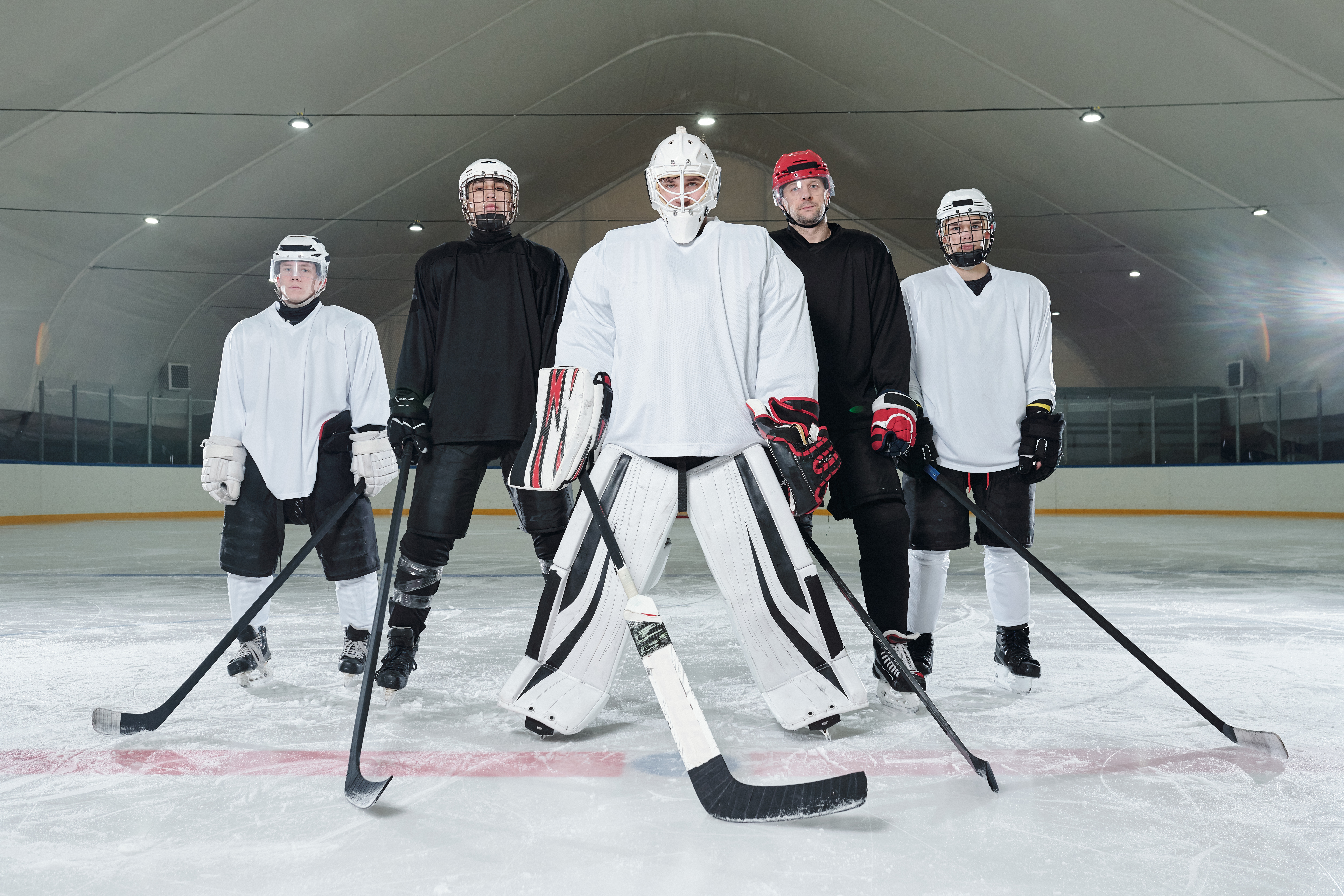 Professional hockey players and their trainer in sports uniform and skates